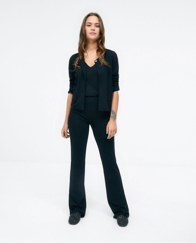 Veste courte sans col. Fermeture par boutons. Noir